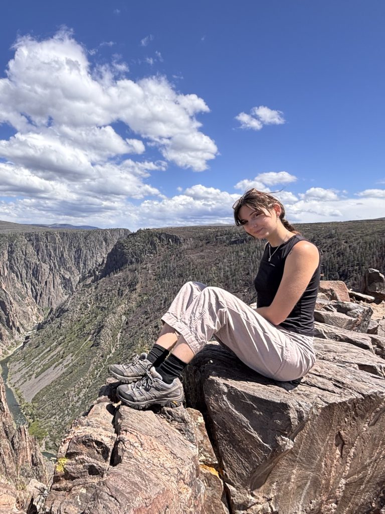 Leah Matthews smiles from a rocky ridge on a mountain